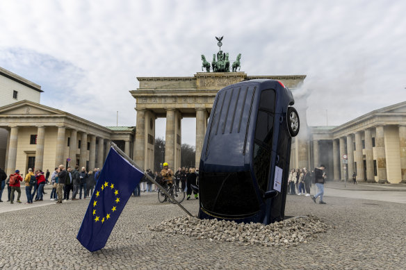 An installation by Greenpeace activists shows an SUV that is seemingly rammed into the pavement in front of the Brandenburg Gate in Berlin, 