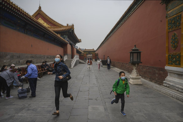 A mother and child run through the Forbidden City in Beijing. 