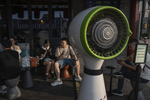 A couple sit next to a large misting fan as they wait for a table outside a popular local restaurant during a heatwave in Beijing, China, on June 23.