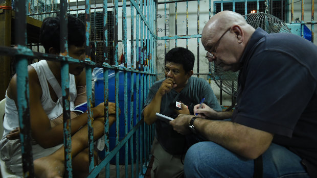 Murdoch, with Filipino journalist Bernard Testa, interviews a survivor of a shooting during a police drug raid, in a holding cell at a police station in Manila in 2016.