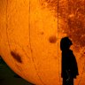 Observers gather on the grass next to an inflatable “blood moon” displayed on the grounds of Princess Sirindhorn AstroPark to watch a total lunar eclipse on Makha Bucha Day on March 03, 2026 in Chiang Mai, Thailand. Telescopes were set up for public viewing by the National Astronomical Research Institute of Thailand, allowing residents to observe the Moon as it rose.