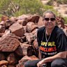 Traditional owner Raelene Cooper with a hand petroglyph on the Burrup Peninsula. 