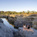 Couple sitting on blanket on the waters edge at Copperfield Gorge.