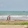 People walk along Citepus Beach, Palabuhan Ratu, Indonesia.