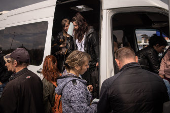 People disembark a van to be registered by police after arriving at an evacuation point for people fleeing Mariupol.