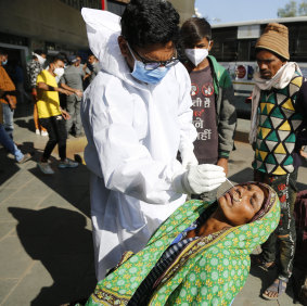 A health worker takes a nasal swab to test for COVID-19 at state transport bus stand in Ahmedabad. 