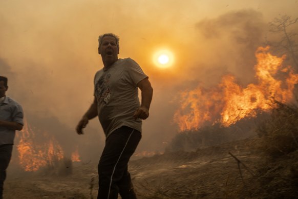 A local reacts as the flames burn trees in Gennadi village, on the Aegean Sea island of Rhodes.