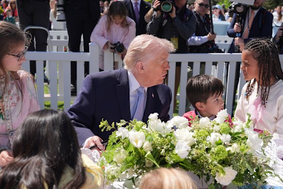 President Donald Trump sits down with children as he participates in the White House Easter Egg Roll.
