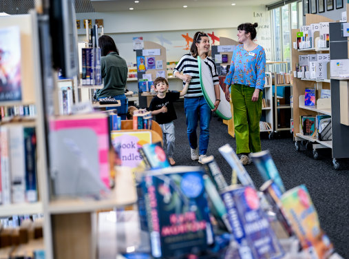 Surf’s up: Inverloch Library staff member Sarah Cantwell (right) and Mirjam White, holding a surfboard, with Henry, 5.