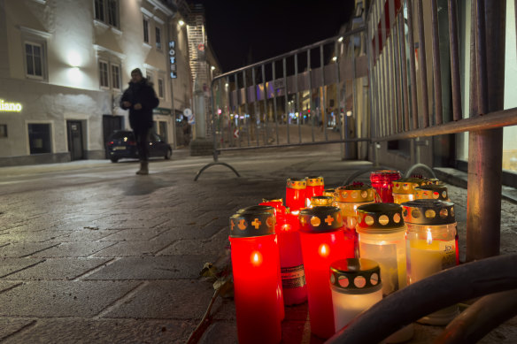 A pedestrian walk past candles at the site of a stabbing attack in Villach, Austria.