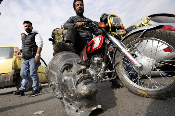 A rebel fighter in Damascus on Sunday with the broken bust of a statue of the late Syrian president Hafez Assad.