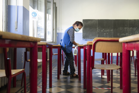 A school worker disinfects desks at the end of the day.
