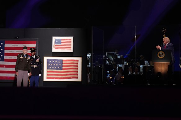 Trump (right) watches as Paris Davis (left), the first Medal of Honour recipient, stands next to the flag from the casket of Abraham Lincoln.
