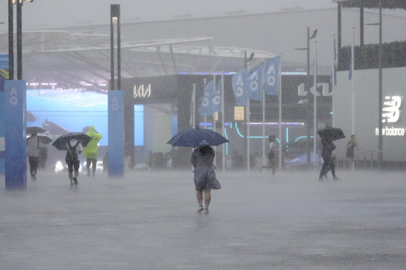 Spectators take cover as rain suspends play in the first round matches at the Australian Open 