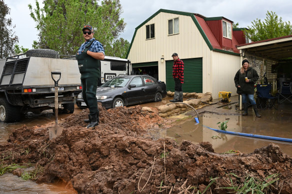 Dan O’Connor (left) standing on a makeshift levee outside a property in Tinamba, eastern Victoria.