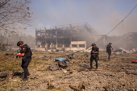 Police officers inspect the scene of the strike on the warehouse in Myla.