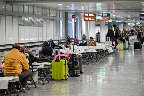 People wait on cots after drone sightings and flight cancellations at Munich Airport. 