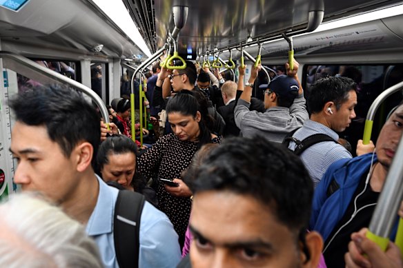 Commuters pack a city-bound metro train during the morning peak.