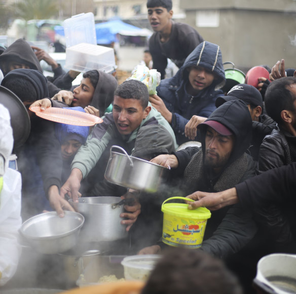 Palestinians line up for free food distribution during the ongoing Israeli air and ground offensive in Khan Younis, Gaza Strip