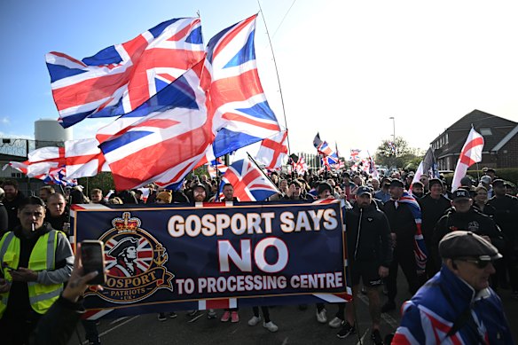 Protestors march during an anti-migrant demonstration outside the Haslar Immigration Removal Centre on October 25, 2026 in Gosport, England. The former naval hospital has been the site of previous demonstrations by groups associated with the Patriot Platform, a anti-migrant collective led by Danny Thomas (known as Danny Tommo), an associate of far-right activist Tommy Robinson (real name Stephen Yaxley-Lennon).