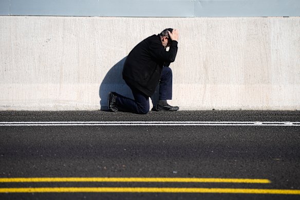 A man takes cover by the side of the road as air raid sirens warn of incoming Iranian missile strikes in Tel Aviv, Israel.