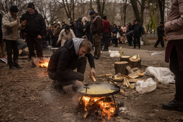 A volunteer puts wood on a fire to cook hot meals for residents in Kherson city centre on December 1.