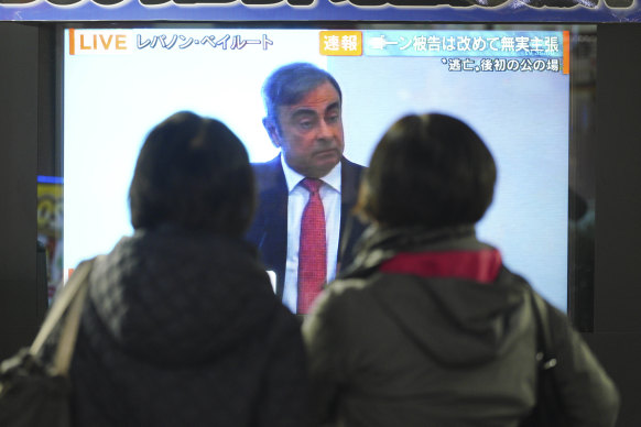 People in Tokyo watch a TV showing a live broadcast of Carlos Ghosn's statement.