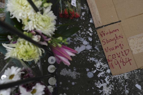 Flowers, candles and a placard are displayed outside the Chinese embassy in London.