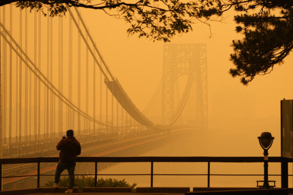 A Man talks on his phone as he looks through the haze at the George Washington Bridge from Englewood Cliffs, New Jersey. 