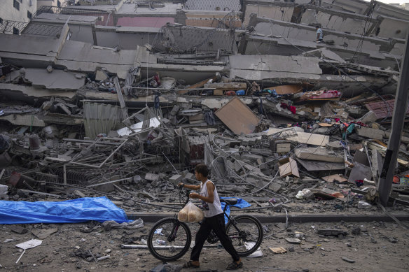 A Palestinian child walks with a bicycle by the rubble of a building after it was hit by an Israeli airstrike, in Gaza City on Sunday