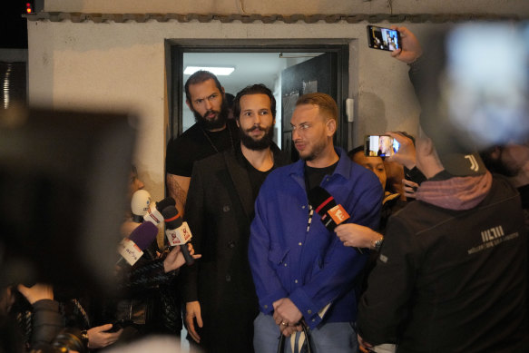 Andrew Tate (solda) ve erkek kardeşi Tristan (ortada), Cuma günü cezaevinden serbest bırakıldıktan sonra Romanya'nın Bükreş kentindeki bir polis gözaltı merkezinin önünde duruyorlar.
