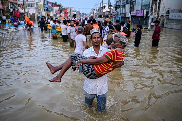 A youth carries an elderly man as they wade through a flooded street after heavy rainfall in Wellampitiya on the outskirts of Colombo yesterday. The death toll from floods and landslides triggered by Cyclone Ditwah has risen to at least 334 people across Sri Lanka, with nearly 400 still missing.