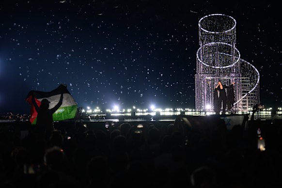 Protesters wave the Palestinian flag as Yuval Raphael performs at Eurovision.