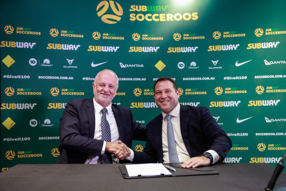 Graham Arnold shakes hands with Football Australia boss James Johnson after signing on as Socceroos coach for four more years.
