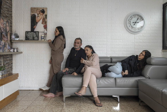 Gal Abdush’s parents, centre, and her sisters at their home in Kiryat Ekron, a small town in central Israel. The photograph on the wall shows Gal and her husband, Nagi.