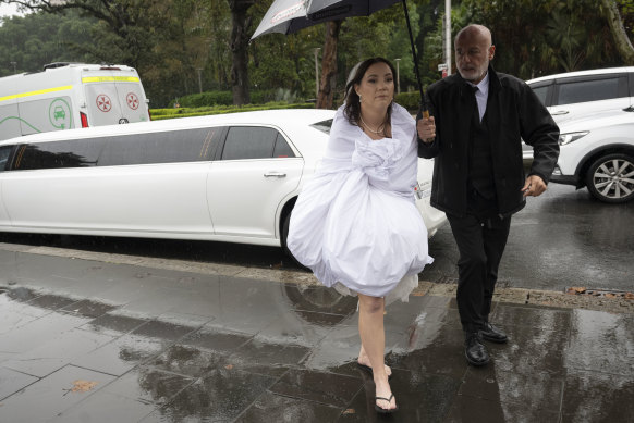 Breanna Cooke protects her wedding dress with a sheet when she arrives at St Mary’s Cathedral for her wedding in Sydney