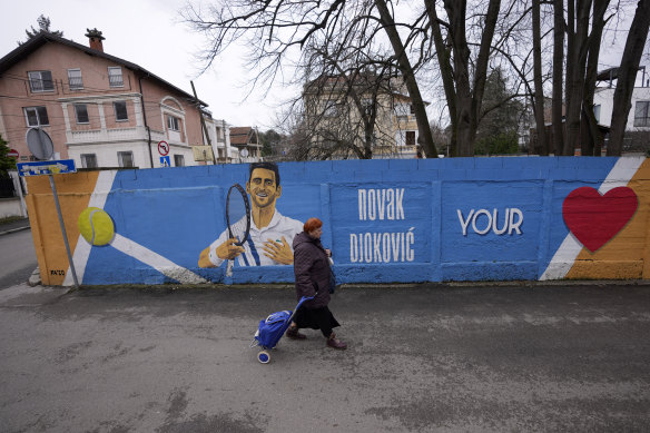 A woman passes a mural depicting Serbian tennis player Novak Djokovic on a wall in Belgrade.