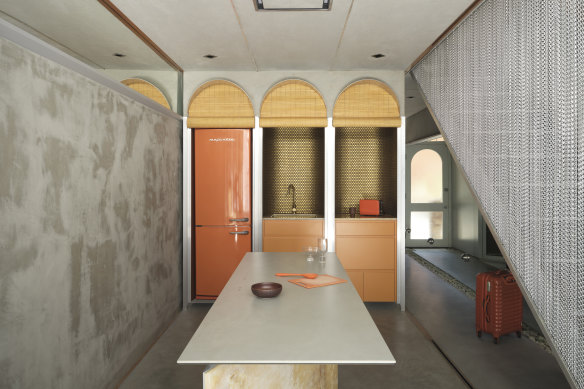 The kitchen, which spills out to the internal courtyard, also has a touch of the glam late 1960s, with the joinery and fridge in the gallery-style kitchen concealed behind operable bamboo blinds.
