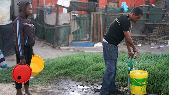 Residents collect water from a communal tap in an informal settlement in Mitchells Plain outside of Cape Town.