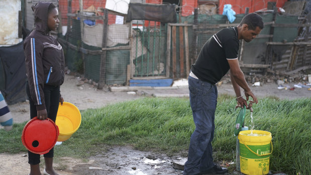 Residents collect water from a communal tap in an informal settlement in Mitchells Plain outside of Cape Town.