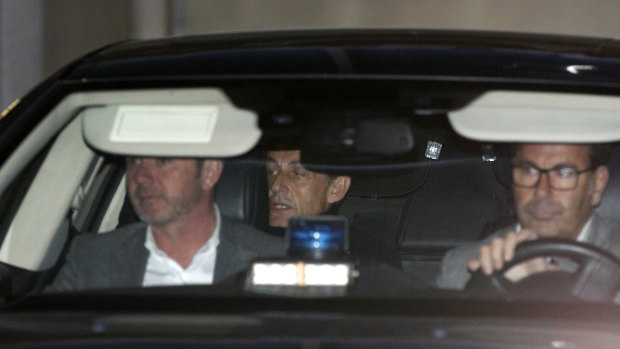 Nicolas Sarkozy, centre, leaves the police station where he was held, in Nanterre, outside Paris, on Wednesday.