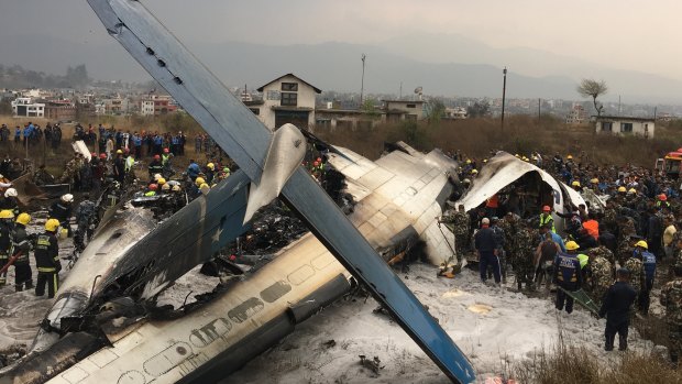 Nepalese rescuers stand near a passenger plane from Bangladesh that crashed at the airport in Kathmandu.