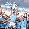 Matheus Nunes holds the Premier League trophy aloft as Manchester City celebrate their title victory.