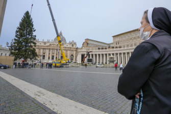 A nun looks as a crane lifts a 28-meter-tall spruce in St. Peter’s Square, to serve as a Christmas tree, at the Vatican.