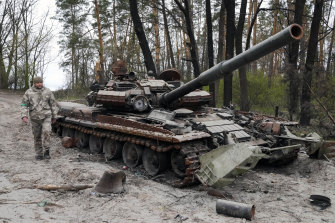 A Ukrainian soldier walks past a Russian tank after recent battles at the village of Moshchun close to Kyiv.