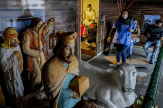 A medical worker and people waiting for a COVID-19 vaccination at a temporary facility next to a Nativity scene at the Christmas market in Offenbach, Germany.