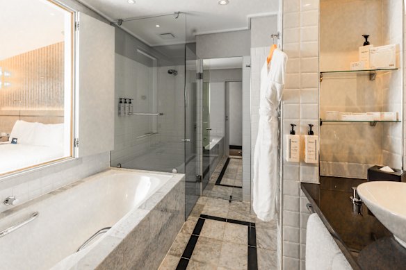 Bathroom with all its mirrors, a bath and a walk-in shower.