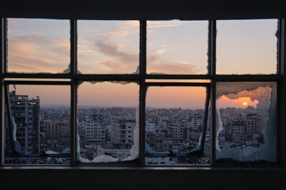 The sun sets behind war-damaged buildings in Gaza City on New Year’s Eve.