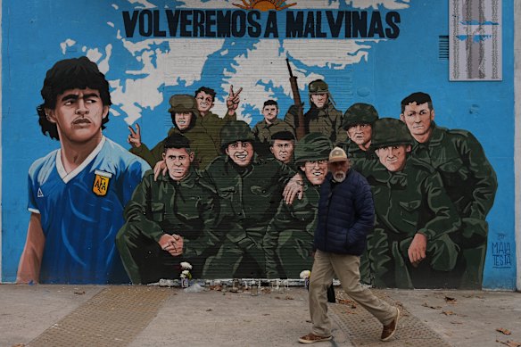 A man walks past a street mural depicting former football star Diego Maradona and Falklands war veterans.
