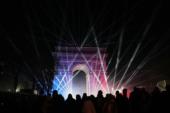 A light show is projected on the Arc de Triomphe.